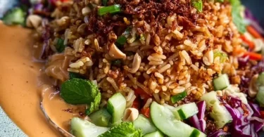 Knuspriger Satay-Reis-Salat mit Gemüse und Erdnusssauce auf einem Teller
