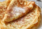 Leckere Pfannkuchen auf einem Teller mit frischen Früchten und Sirup