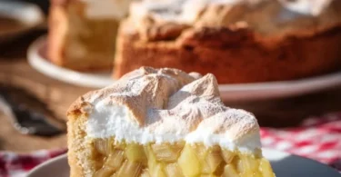 Rhabarberkuchen mit Baiser auf einem Teller, dekoriert mit frischen Früchten